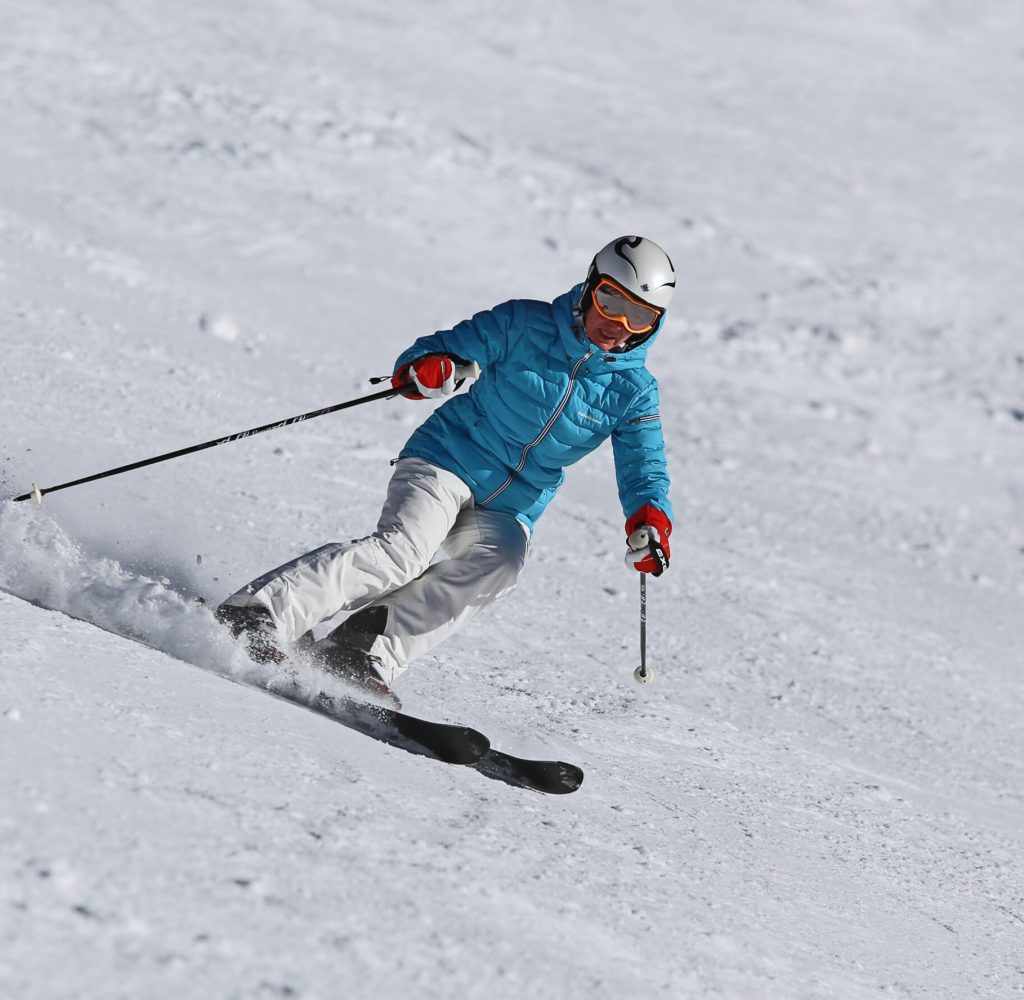 Frau in Skianzug fährt Piste runter